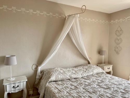 a bedroom with a bed with a canopy and two night stands at Hotel L'Orangeraie in Le Lavandou