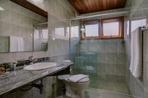 a bathroom with a toilet and a sink and a shower at Apart Central MV in Monte Verde