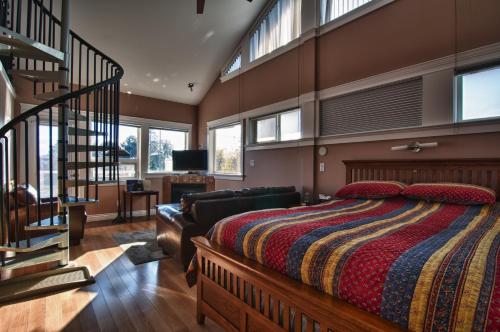 a bedroom with a large bed and a staircase at Birds of a Feather Ocean Lagoon Victoria Condos in Colwood