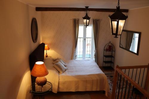 ein Schlafzimmer mit einem Bett mit einer Lampe und einem Fenster in der Unterkunft Clarberg - B&B in Saint-André-de-Roquepertuis