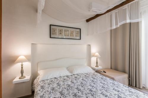 ein weißes Schlafzimmer mit einem Bett und zwei Lampen in der Unterkunft The Bell in Comiso