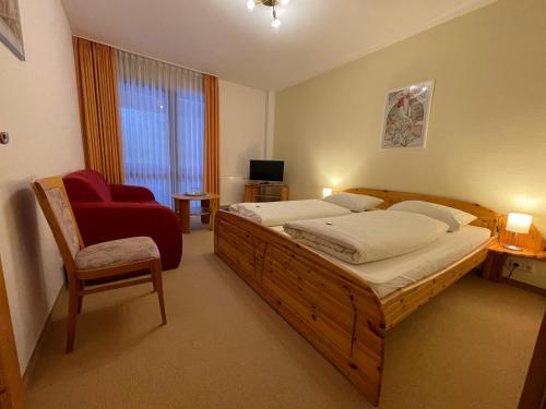 a bedroom with a large bed and a red chair at Waldhotel Zöbischhaus in Bad Reiboldsgrün