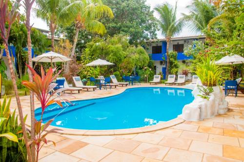 a pool at a resort with chairs and umbrellas at Pousada Arriba Pipa in Pipa