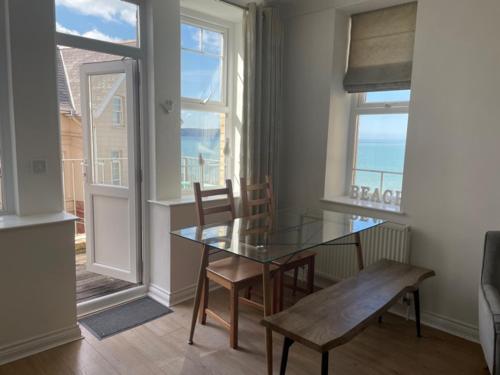 Woolacombe Seaside Apartment في ولاكومب: غرفة طعام مع طاولة زجاجية وكراسي ونافذة