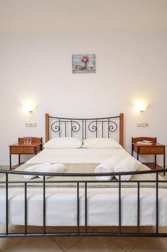 a bedroom with a bed with white sheets and two tables at Asterias Studios in Agia Anna Naxos