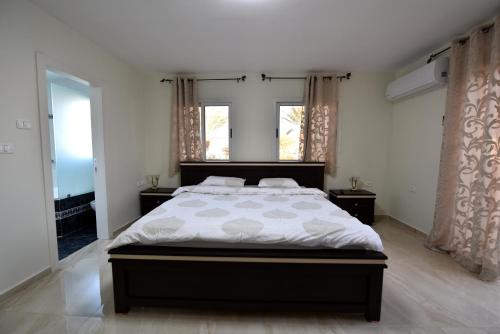 Un dormitorio con una cama grande y dos ventanas. en Amazing Villa, en Eilat