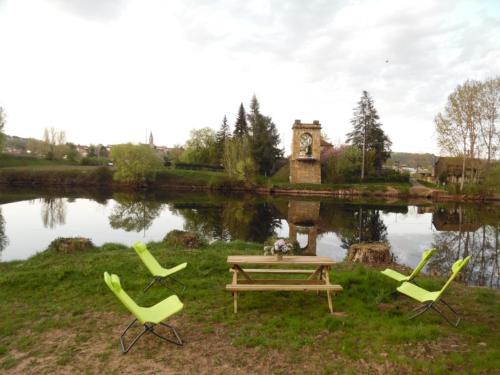 three chairs and a picnic table in front of a lake at Le Pont de Livinhac in Decazeville