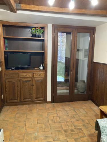 sala de estar con TV de pantalla plana y puertas correderas de cristal en La casetta nel granaio en Capranica
