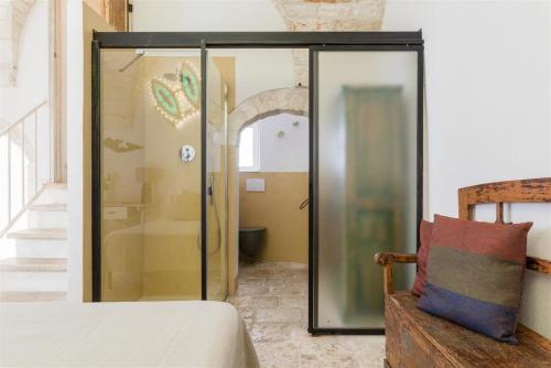 een glazen douche in een slaapkamer met een bed bij Chianca Antica in Ostuni