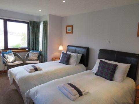 a hotel room with two beds and a chair at Meadowbank Guest House in Portree