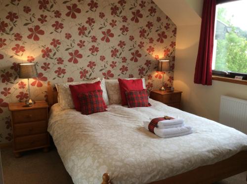 a bedroom with a bed with red pillows and a window at Meadowbank Guest House in Portree