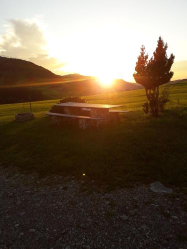 a sunset in a field with a tree and a building at Ferienwohnung Brülisauer in Brülisau