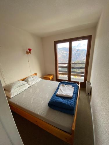 une chambre avec un lit avec une grande fenêtre dans l'établissement Amethyste, à Saint-Gervais-les-Bains