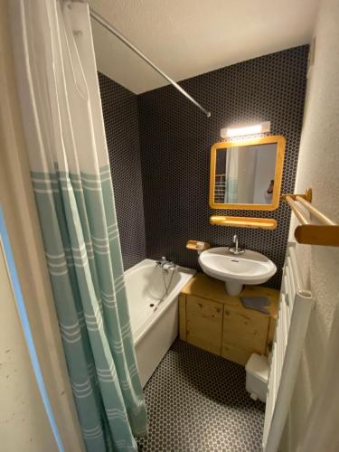 une salle de bain avec un lavabo, une baignoire et un miroir dans l'établissement Amethyste, à Saint-Gervais-les-Bains