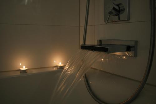 a bathroom with a mirror and a sink with lights at Lake FeWo Santorini in Oberteuringen