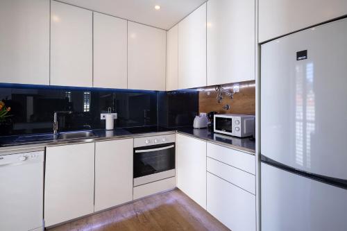 a white kitchen with white cabinets and a microwave at Alcântara Factory I in Lisbon