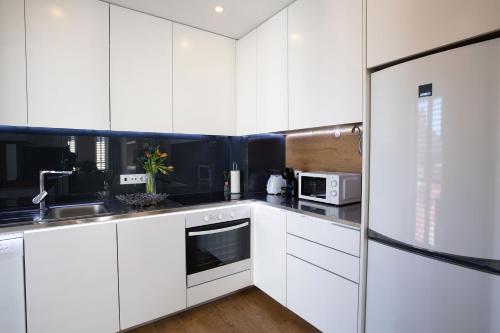 a white kitchen with white cabinets and a refrigerator at Alcântara Factory I in Lisbon