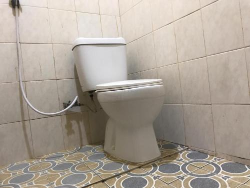 a white toilet in a bathroom with a tile wall at KoolKost Syariah near Pelabuhan Tanjung Priok (Minimum Stay 6 Nights) in Jakarta