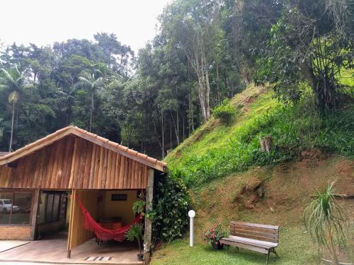 una casa con un banco al lado de una colina en Chalé Vale da Mata, en Visconde De Maua