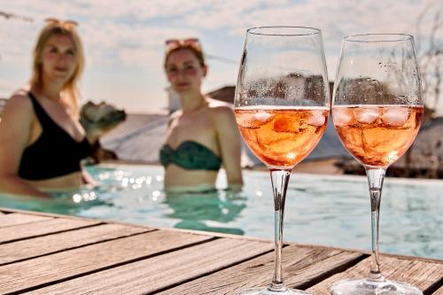 DysArt Boutique Hotel - Solar Power في كيب تاون: سيدتان في حمام سباحة مع كأسين من النبيذ