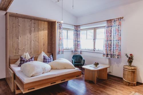 a bedroom with a bed and a chair and windows at Pension Seighof in Saalbach Hinterglemm