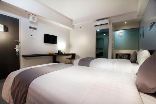 a hotel room with two beds and a television at Neo Hotel Tendean Jakarta by ASTON in Jakarta