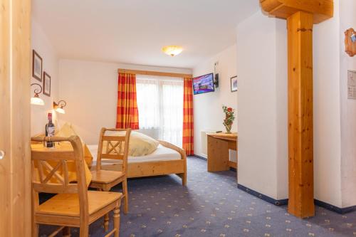 a bedroom with a bed and a table and a chair at Pension Seighof in Saalbach Hinterglemm