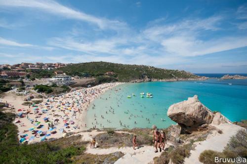 a beach with a bunch of people in the water at Relais Du Port in Santa Teresa Gallura