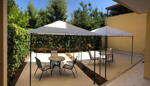 2 mesas y sillas con sombrillas en un patio en B&B SALento Garden, en Lecce