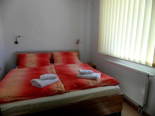 a bedroom with a red bed with towels on it at Apartmány Dalila in Rajecké Teplice