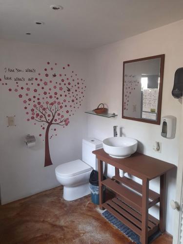a bathroom with a toilet and a tree on the wall at Posada Casa Topiltzin in Tepoztlán