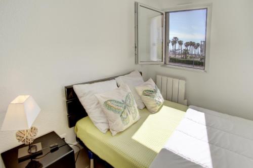 Cette petite chambre comprend un lit avec des oreillers et une fenêtre. dans l'établissement T2 A DEUX PAS DES PLAGES QUARTIER DES QUILLES, à Sète