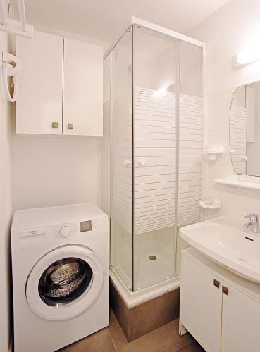 une salle de bain blanche avec une machine à laver et un lavabo dans l'établissement T2 A DEUX PAS DES PLAGES QUARTIER DES QUILLES, à Sète