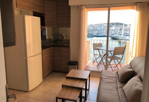 a living room with a couch and a kitchen with a balcony at studio la grande roue VUE MAGNIFIQUE in Cap d'Agde