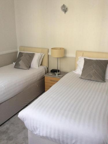 a bedroom with two beds and a lamp on a night stand at The Epperstone in Llandudno