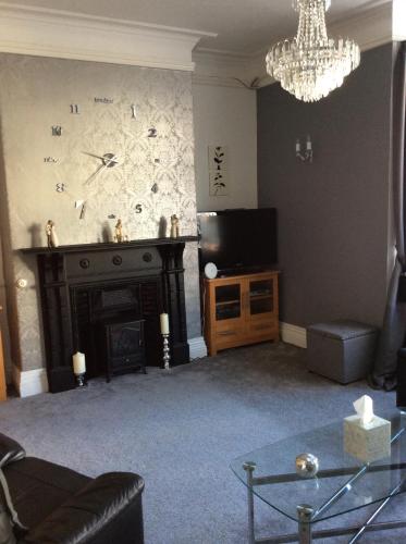a living room with a fireplace and a chandelier at The Epperstone in Llandudno