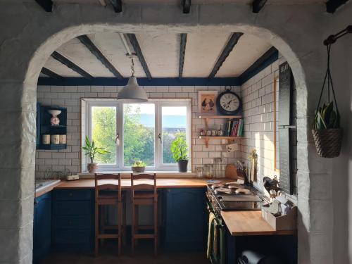 a kitchen with blue cabinets and a large window at Old Road Cottage Pet Friendly Outdoors Beaches in Neath