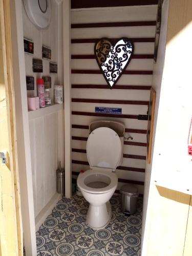 a toilet in a bathroom with a heart on the wall at Havre de paix au bords de l'Eure - divers hébergements in Neuilly