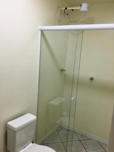 uma casa de banho com um WC e uma cabina de duche em vidro. em Flat no centro em Chapecó
