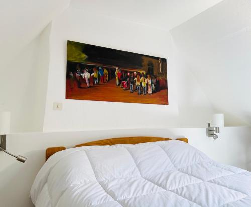 a bedroom with a bed with a painting on the wall at An ti Bihan, Gite Breton à la campagne in Tonquédec