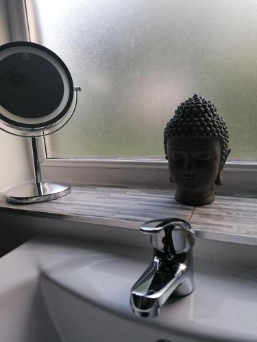 a head statue sitting on a window sill next to a mirror at Chota Gher Apartment in Widnes