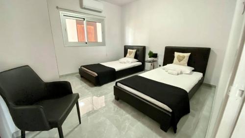 Habitación pequeña con 2 camas y silla en Napa Court 2 en Ayia Napa