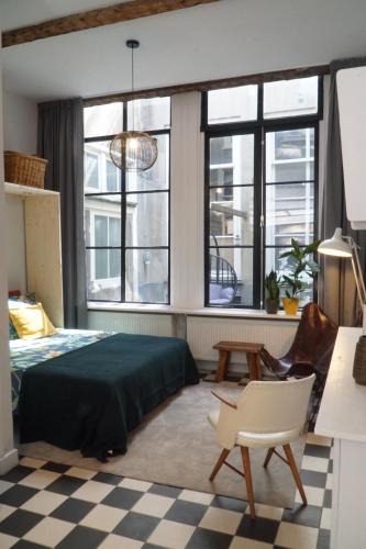 een slaapkamer met een bed, een stoel en ramen bij Steeg 8 in Dordrecht