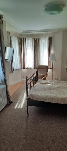 a hotel room with a bed and a chair and windows at Villa Shafaly in Mariánské Lázně