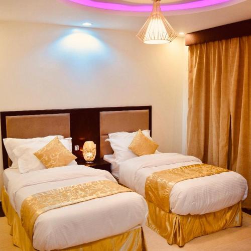 Habitación de hotel con 2 camas y lámpara de araña. en شاليهات رميس للعائلات RAMIS Chalet en Abha