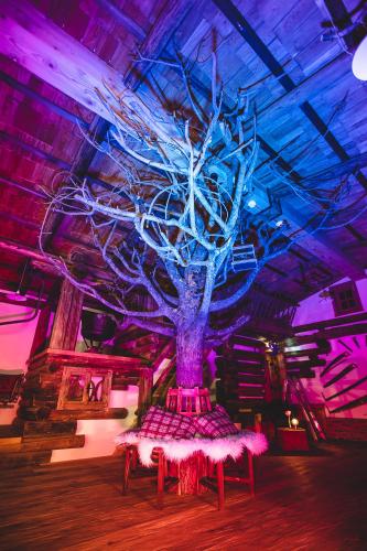 a large tree in a room with a table at Pension Seighof in Saalbach Hinterglemm