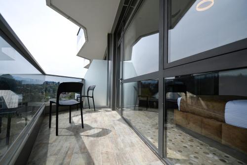 a room with glass windows and a chair on a balcony at Calligraphy Hotel and Cottages in Mtsvane Kontskhi