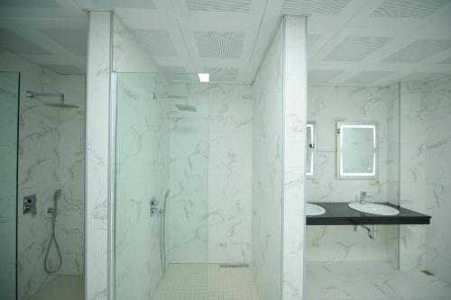 a white bathroom with a shower and a sink at Calligraphy Hotel and Cottages in Mtsvane Kontskhi
