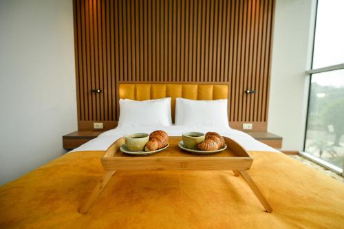 a tray with two croissants and two cups on a bed at Calligraphy Hotel and Cottages in Mtsvane Kontskhi