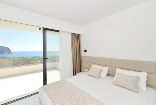 a bedroom with a white bed and a large window at Villa Zen Hill in Petrovac na Moru